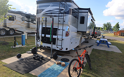 The rear of a diesel motorcoach on a cement RV pad with picnic table and bicycle at a Alabama luxury rv resort 