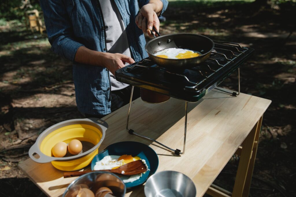 man cooking eggs on a camp propane stove.