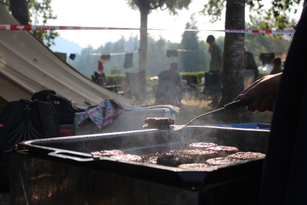 man making burgers while camping