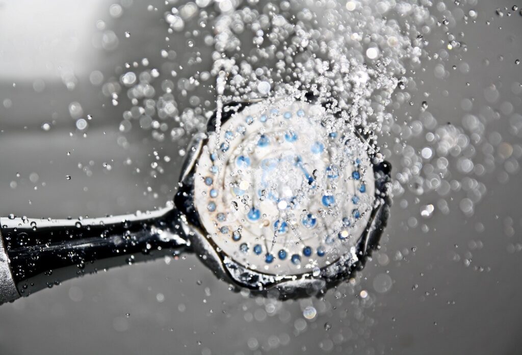  Showerhead with water flowing out, creating a stream of droplets. The showerhead is a sleek chrome design and has multiple nozzles for a refreshing and invigorating shower experience.