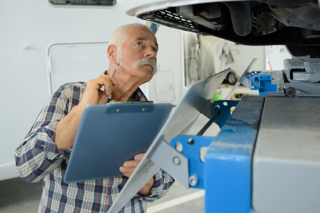 older man inspecting the undercarriage of an RV for hidden costs